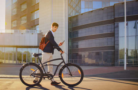 Confident young businessman walking with bicycle on the street in town.の写真素材
