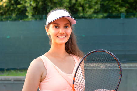 Pretty sportswoman with racquet at the tennis court. Healthy lifestyle.の写真素材
