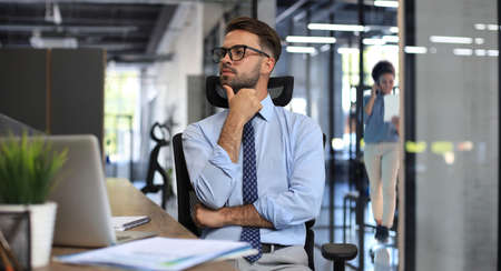 Focused businessman thinking at modern office into report file calculating stock market earnings, startup businessの写真素材