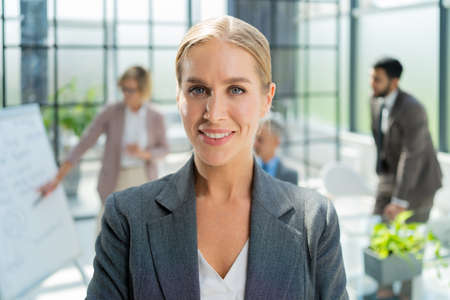 Business woman with her staff, people group in background at modern bright office indoors