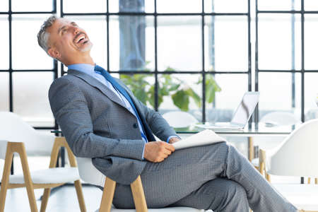 Confident pensive mature business man in modern officeの写真素材