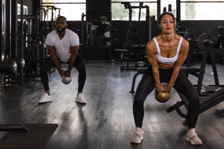 Fit and muscular couple focused on lifting a dumbbell during an exercise class in a gymの写真素材