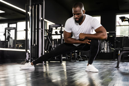 Muscular african man at the gym doing stretching exercises on the floor