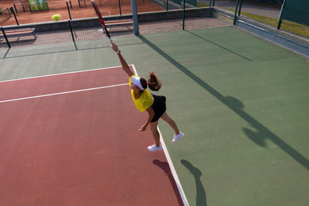 Professional equipped female tennis player beating hard the tennis ball with racquet. Top viewの写真素材