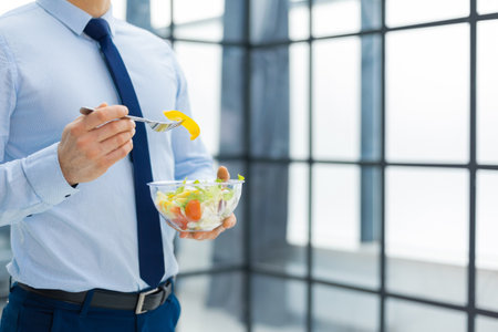 Unrecognizable businessman eating a vegetables salad for lunch, healthy and lifestyle conceptの写真素材