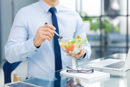 Unrecognizable businessman eating a vegetables salad for lunch, healthy and lifestyle conceptの写真素材