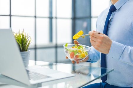 Unrecognizable businessman eating a vegetables salad for lunch, healthy and lifestyle conceptの写真素材