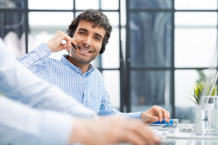 Portrait of a smiling young businessman working on computer at office with his colleague