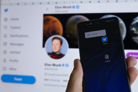 MINSK, BELARUS - July 07, 2023: Uninstalling of the twitter app on smartphone following the release of a competitive new app Threads from Meta Platforms. In the background of Elon Musks Twitter pageのeditorial素材