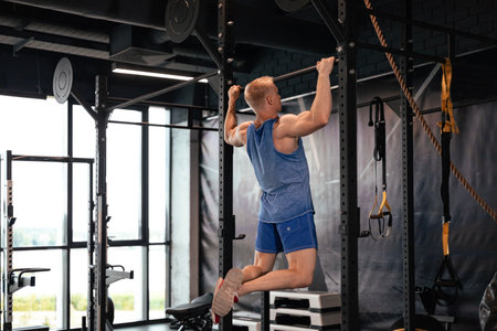 Fit and muscular man shakes his back on the simulator. Back view