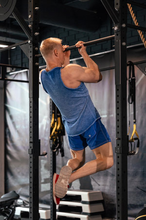Fit and muscular man shakes his back on the simulator. Back view