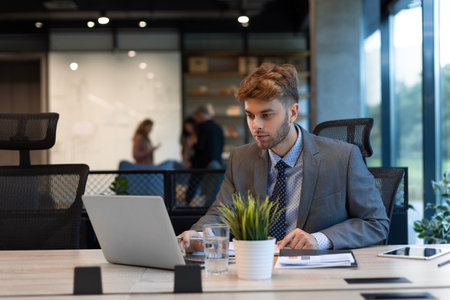 Portrait of young man sitting at his desk in the officeの写真素材