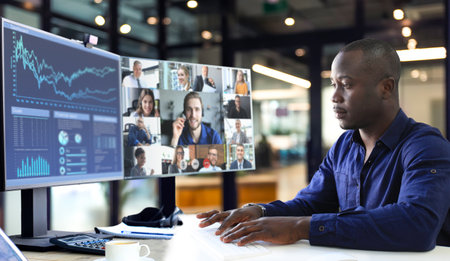 African american businessman talking to his colleagues in video conference. Multiethnic business team working from office using PC, discussing financial report of their companyの写真素材