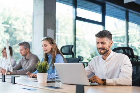 Portrait of call center worker accompanied by his team. Smiling customer support operator at work