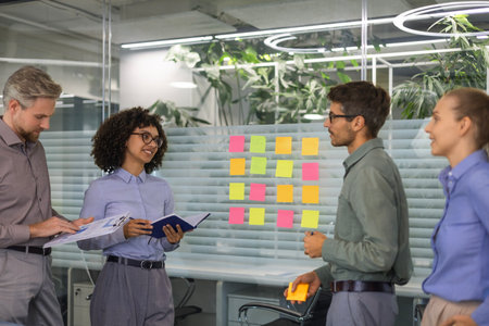 Businesspeople talking in their diverse team during a brainstorming session with sticky notes on...