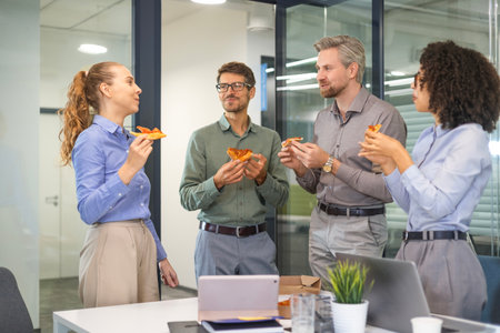 Happy multiracial colleagues have fun at lunch break in office. Excited workers celebrate shared win ordering takeaway pizza.の写真素材