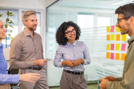 Businesspeople talking in their diverse team during a brainstorming session with sticky notes on...