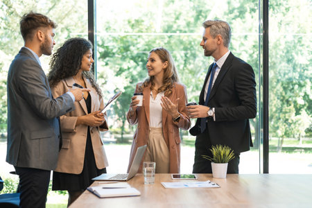 Four business people discussing work together using a tablet in a modern officeの写真素材
