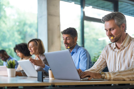 Portrait of call center worker accompanied by his team. Smiling customer support operator at work
