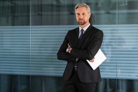 Smiling businessman standing in office with tablet.の写真素材