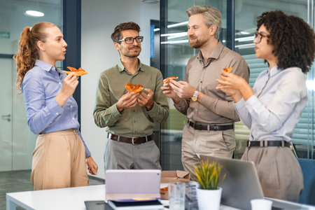 Happy multiracial colleagues have fun at lunch break in office. Excited workers celebrate shared win ordering takeaway pizza.の写真素材