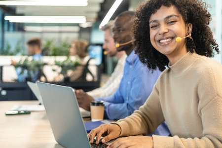Portrait of call center worker accompanied by her team. Smiling customer support operator at workの写真素材
