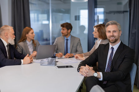 Portrait of businessman sitting at his desk in the office and smiling looking at camera.