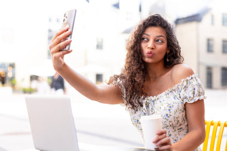 Young pretty brunette woman outdoors in summer city take a selfie by mobile phone
