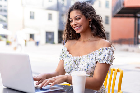 Happy nice woman working on laptop in street cafe