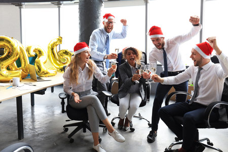 Business people are celebrating holiday in modern office drinking champagne and having fun in...