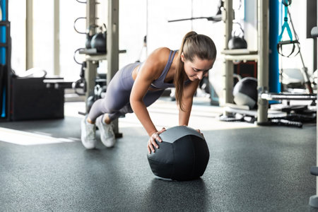 Fit and muscular woman exercising with medicine ball at gym