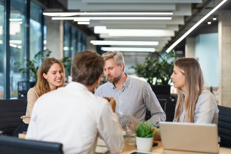 Group of confident business people in smart casual wear working together while sitting at the desk...