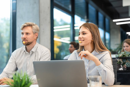Portrait of call center worker accompanied by her team. Smiling customer support operator at workの写真素材