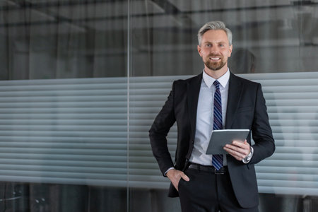 Smiling handsome businessman manager standing in office with tablet computer.の写真素材