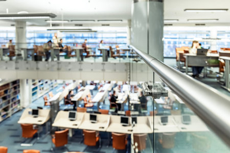 In a two-story office, employees talk and sit at their desks and work on computers.の写真素材