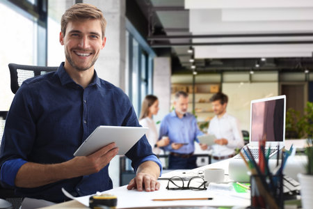 Young modern business man working using digital tablet while sitting in the officeの写真素材