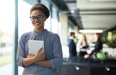 Young elegant business woman standing with digital tablet near office window.の写真素材