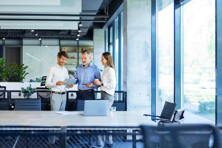 Group of business people standing together and discussing their work and projects, having a team meeting in an officeの写真素材