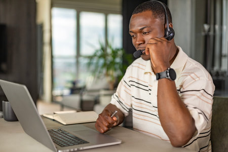 Concentrated african freelancer businessman using laptop for video conference, working remotely...