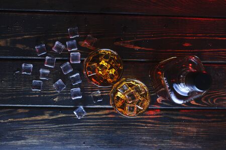 Two glasses of whiskey with ice cubes served on wooden planks.Studio photographyの写真素材
