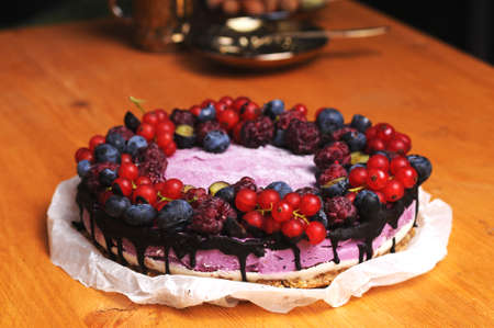 Festive cake, blueberry and blackberry sponge cake with cream cheese inside on a plate on a wooden table, horizontal view from above.の写真素材