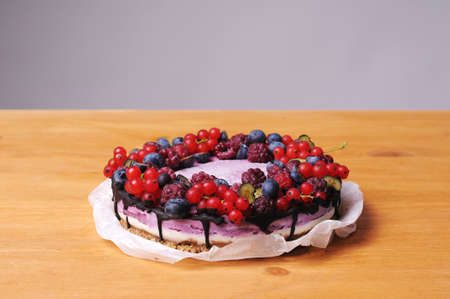 Festive cake, blueberry and blackberry sponge cake with cream cheese inside on a plate on a wooden table, horizontal view from above.の写真素材