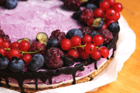 Festive cake, blueberry and blackberry sponge cake with cream cheese inside on a plate on a wooden table, horizontal view from above. Macro photo.の写真素材