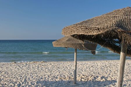 Old fashioned umbrellas at the mediaterranean beach. Monastir, Tunisia