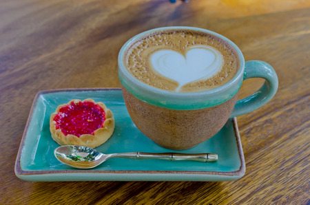 cup of coffee, heart shape with strawberry biscuit on wood background.の写真素材