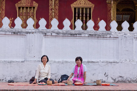 lUANG PRABANG, LAO - MAY 12:Tourist waiting for the monks. Every day very early in the morning, the monks walk the streets to beg give food offerings to a Buddhist monk on May 12, 2014 in Luang Prabang, Laos.のeditorial素材