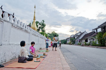 lUANG PRABANG, LAO - MAY 12:Tourist waiting for the monks. Every day very early in the morning, the monks walk the streets to beg give food offerings to a Buddhist monk on May 12, 2014 in Luang Prabang, Laos.のeditorial素材