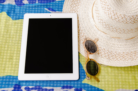concept of summer traveling with smartphone sunglasses and hat on cloth.の写真素材