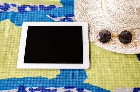 concept of summer traveling with smartphone sunglasses and hat on cloth.