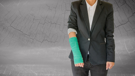 Injured businesswoman with green cast on hand and arm on blurred abstract background .の写真素材